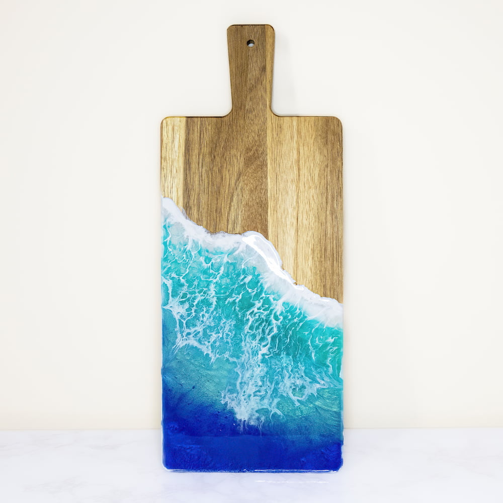 Sample of resin home decor where image is of a cutting board with a resin ocean theme: white waves into a deep blue.