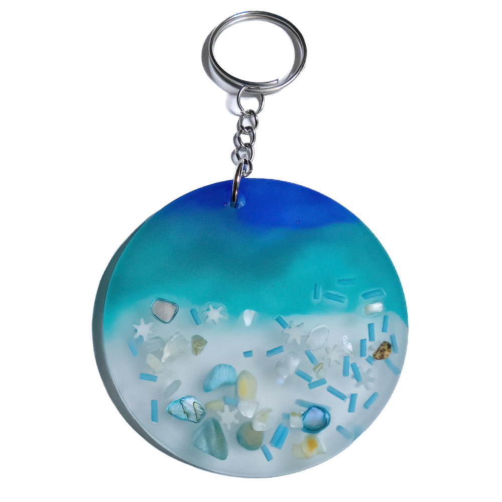 Ocean themed keychain with plastic sprinkles, white star shapes, and blue rocks to resemble the ocean.