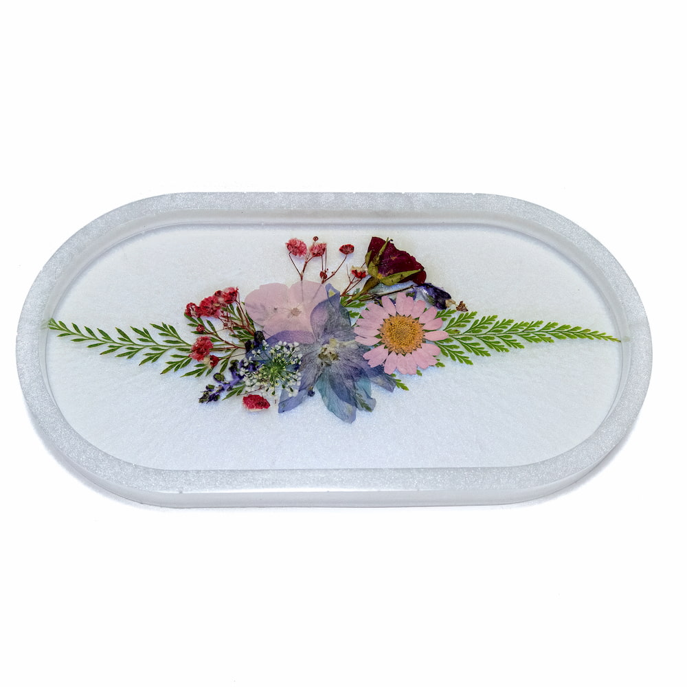 Resin trinket tray with a pressed flower arrangement on the inside.