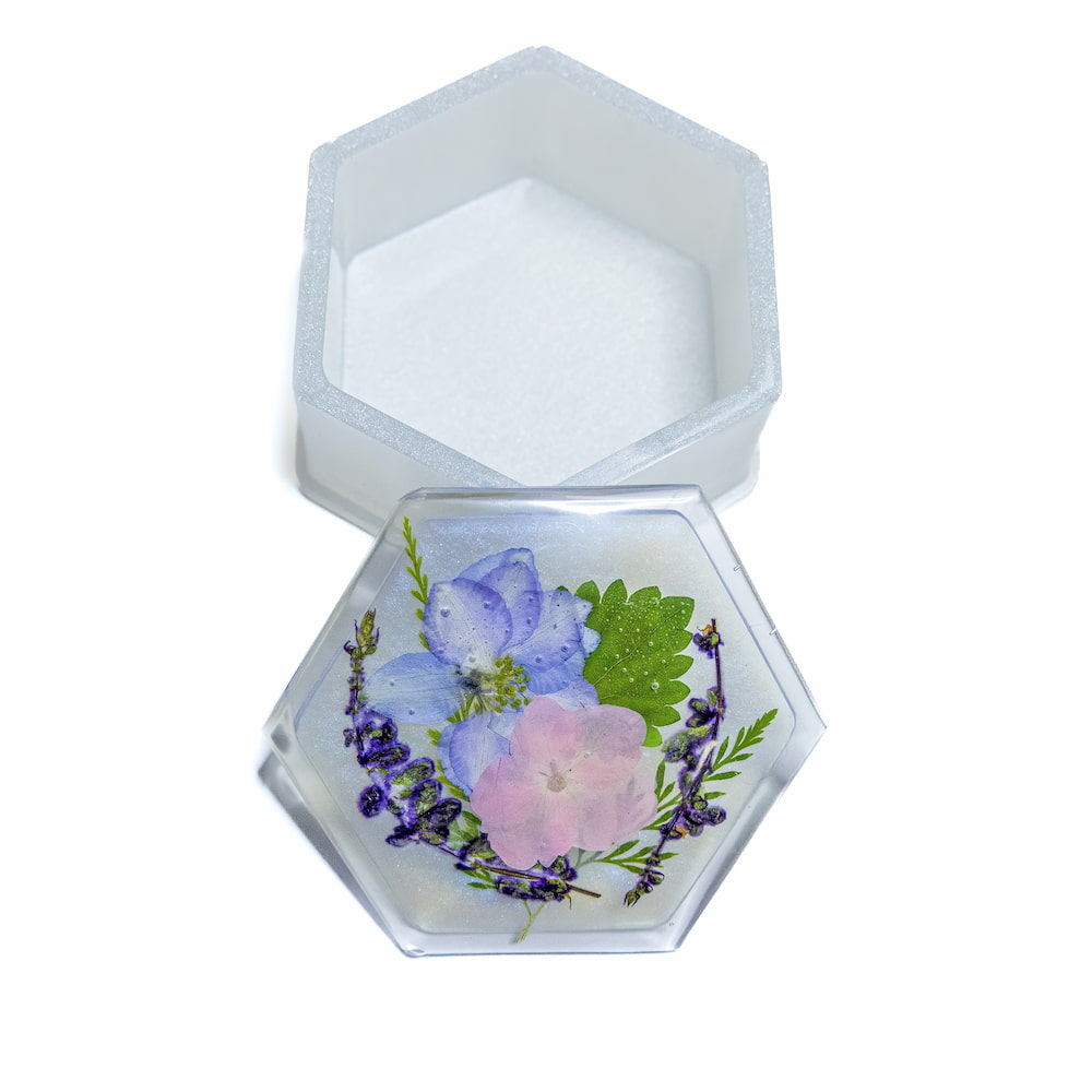 Hexagonal resin trinket container with pressed flowers on lid.